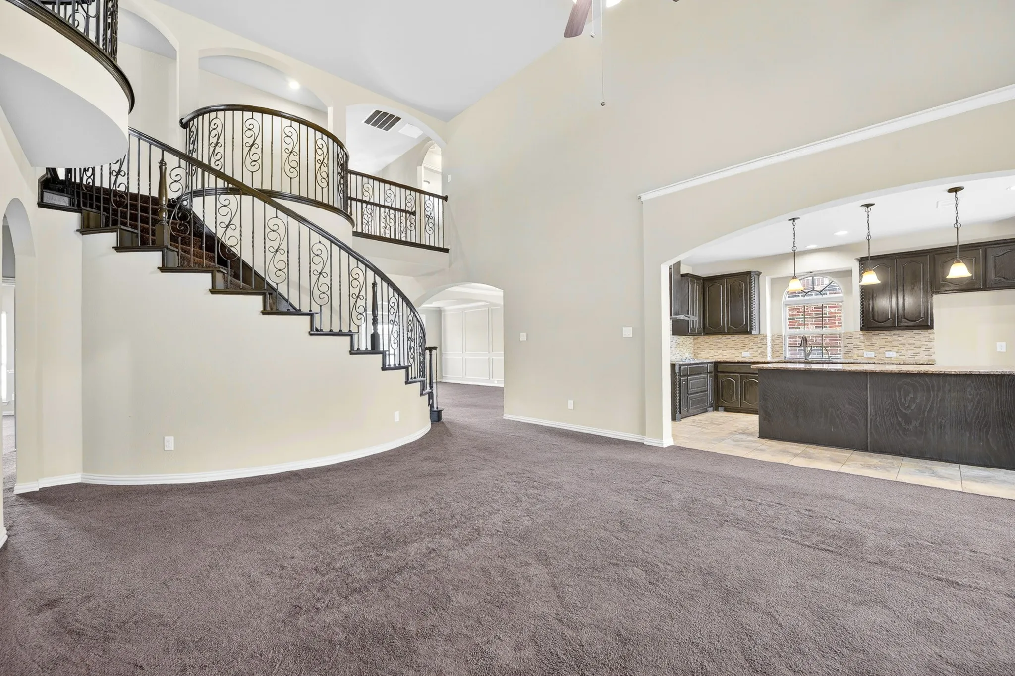 This property features a grand spiral staircase with ornate iron balusters, high ceilings, and an open layout that incorporates the kitchen