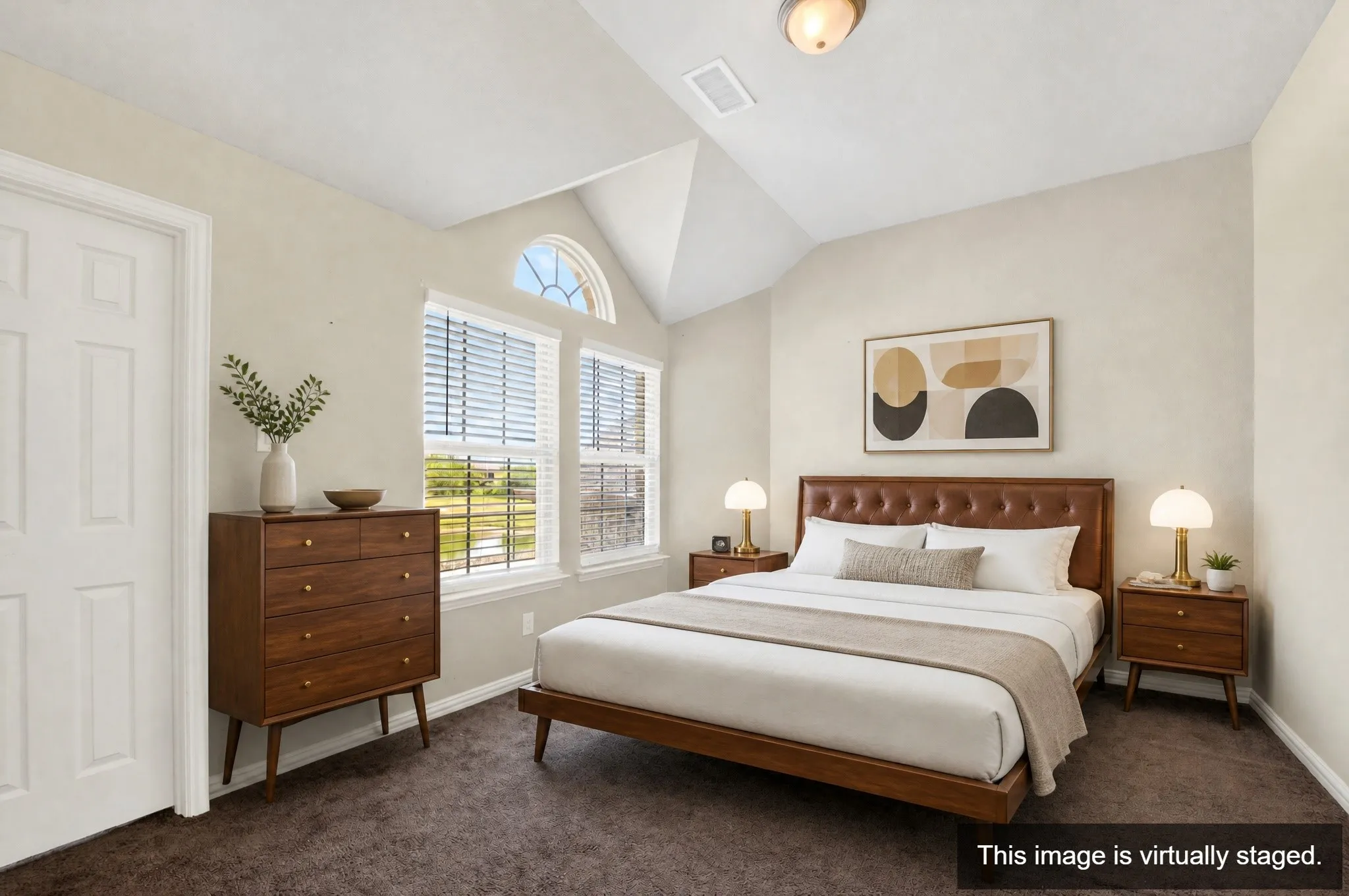 Vaulted ceiling bedroom featuring ample natural light from multiple windows, including an arched transom window
