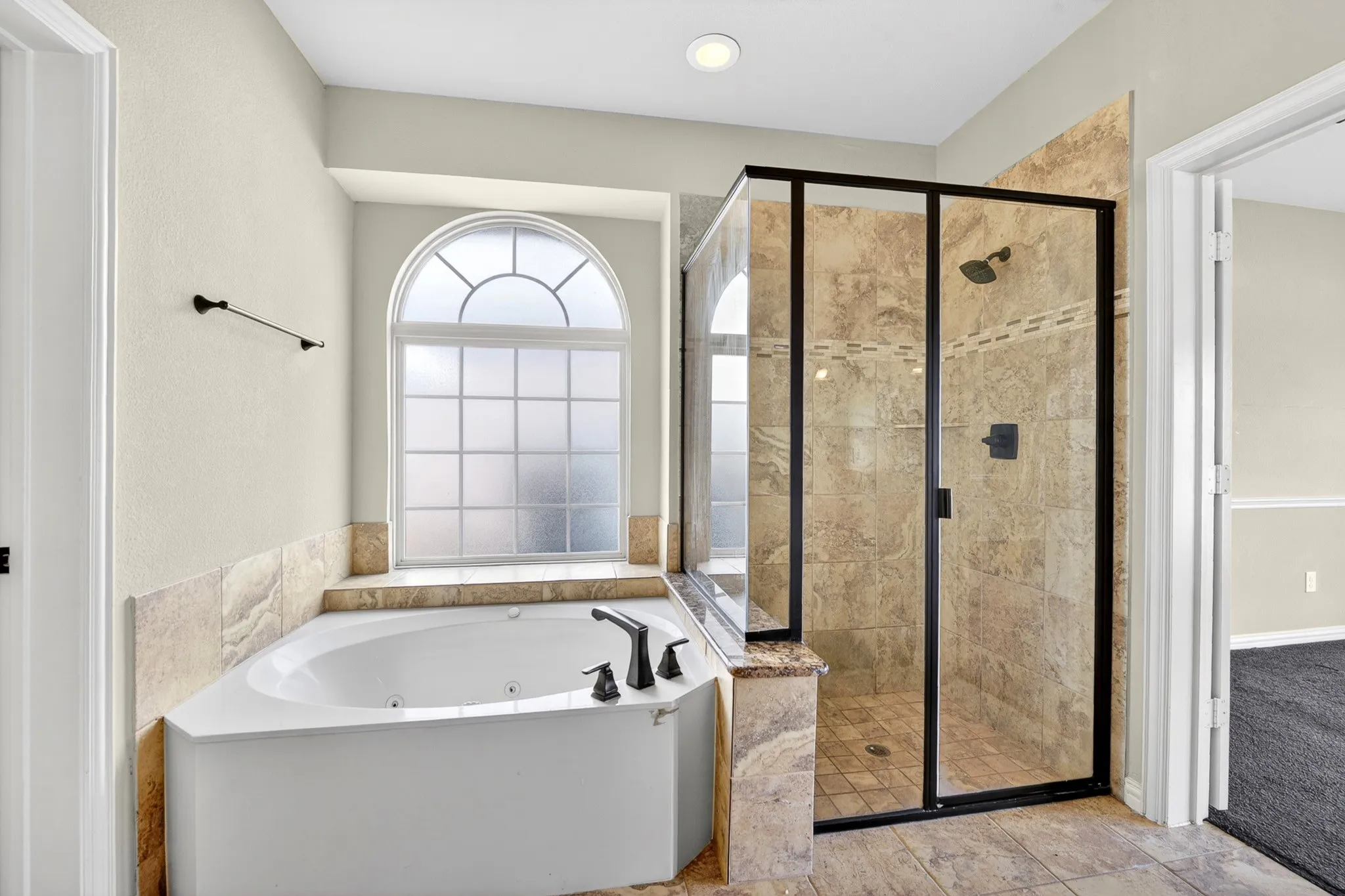The bathroom features a corner soaking tub and a tiled walk-in shower with a glass enclosure