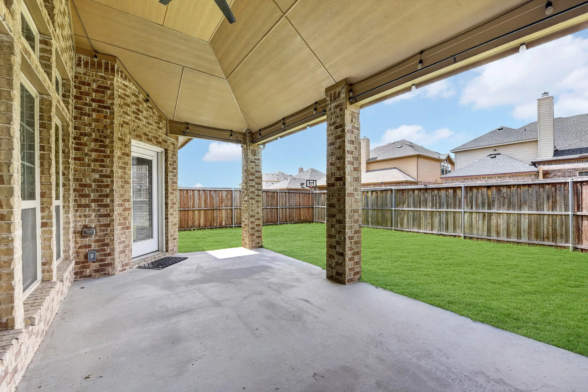 The property features a covered patio with a concrete surface, brick columns, and a ceiling fan
