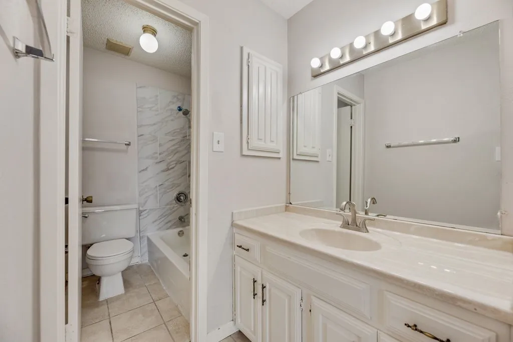 Bathroom with vanity, tile patterned floors, and washtub / shower combination