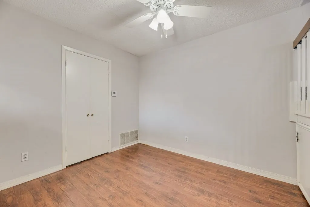Unfurnished bedroom with wood finished floors, ceiling fan, and a textured ceiling