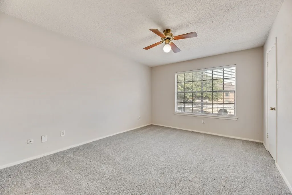 Carpeted spare room featuring a ceiling fan and a textured ceiling