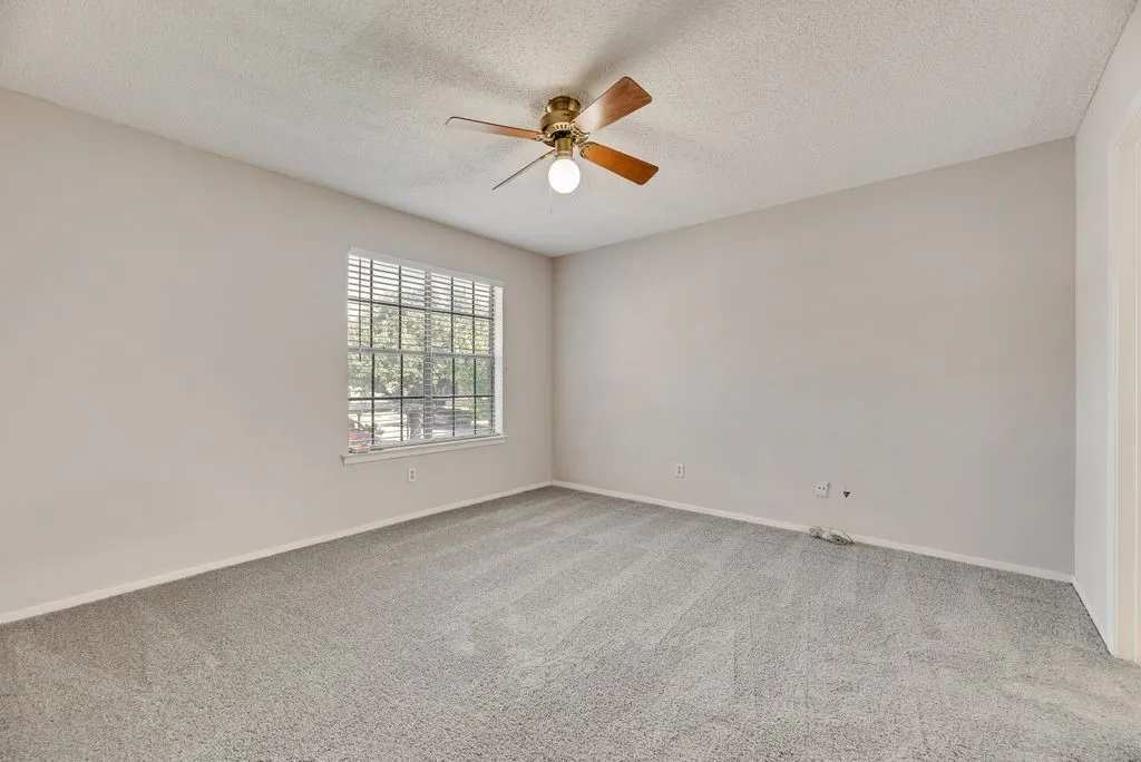 Carpeted spare room with a ceiling fan and a textured ceiling