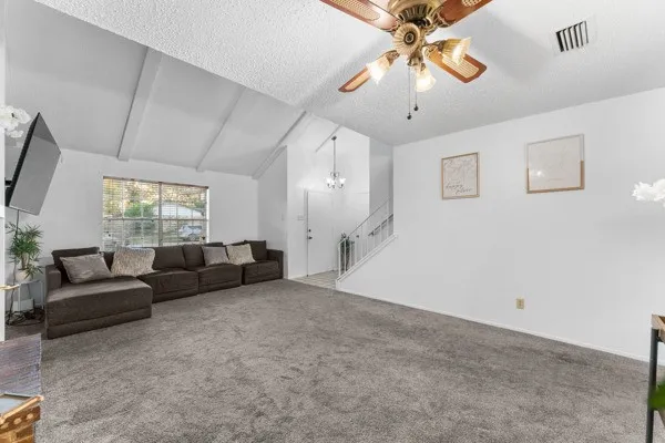 Living room with carpet floors, a chandelier, a textured ceiling, and a ceiling fan