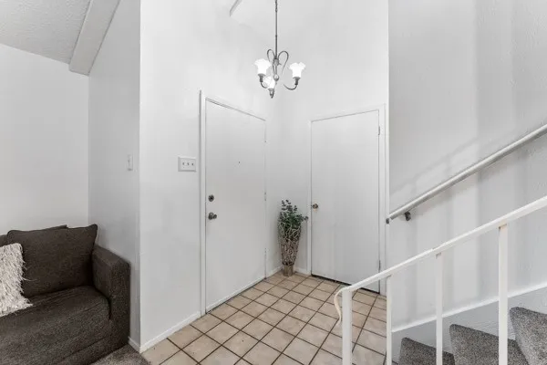 Entrance foyer featuring stairway, tile patterned flooring, a textured ceiling, and a chandelier