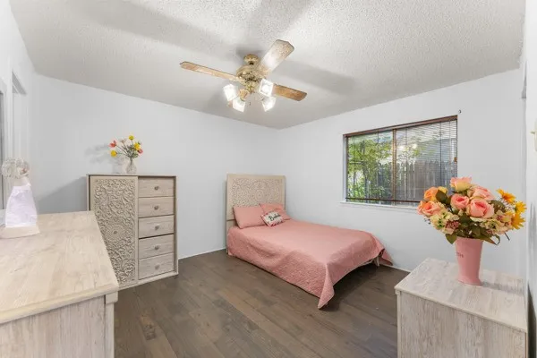 Bedroom featuring dark wood-type flooring, a textured ceiling, and a ceiling fan