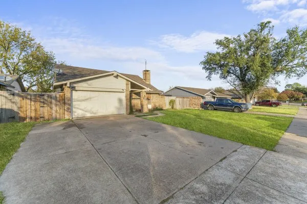 View of front facade with driveway, a chimney, and a garage