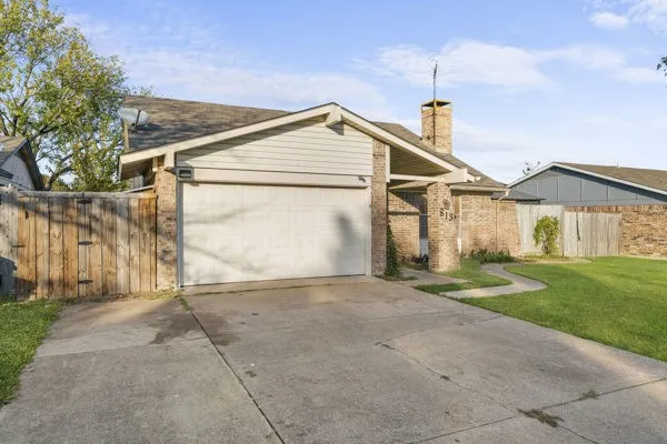 View of front of home featuring concrete driveway, a garage, a chimney, and brick siding