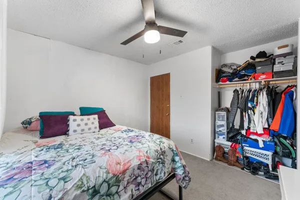 Carpeted bedroom featuring a closet, a ceiling fan, and a textured ceiling
