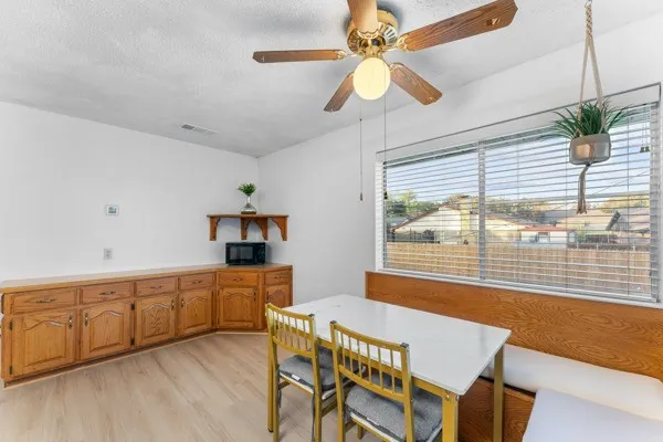 Dining room with a textured ceiling, light wood finished floors, and a ceiling fan