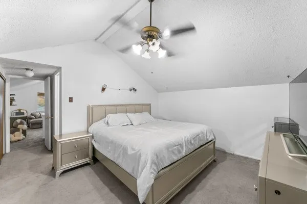 Carpeted bedroom featuring a textured ceiling and a ceiling fan
