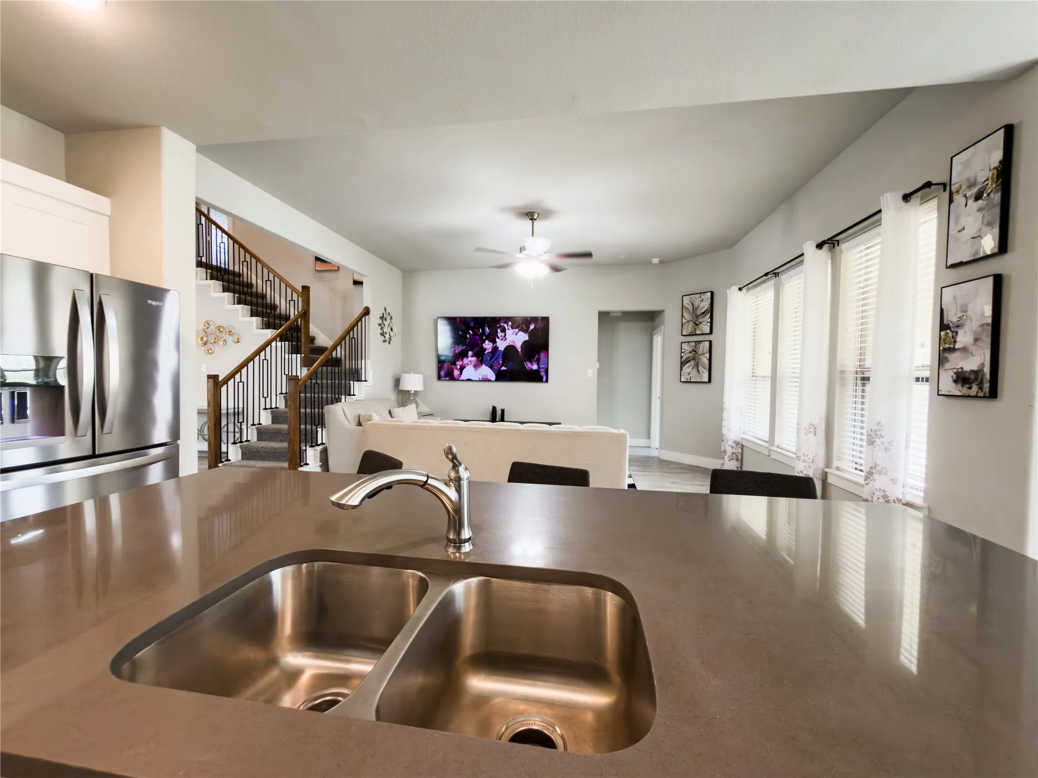 Kitchen with stainless steel refrigerator with ice dispenser, ceiling fan, open floor plan, and dark stone countertops