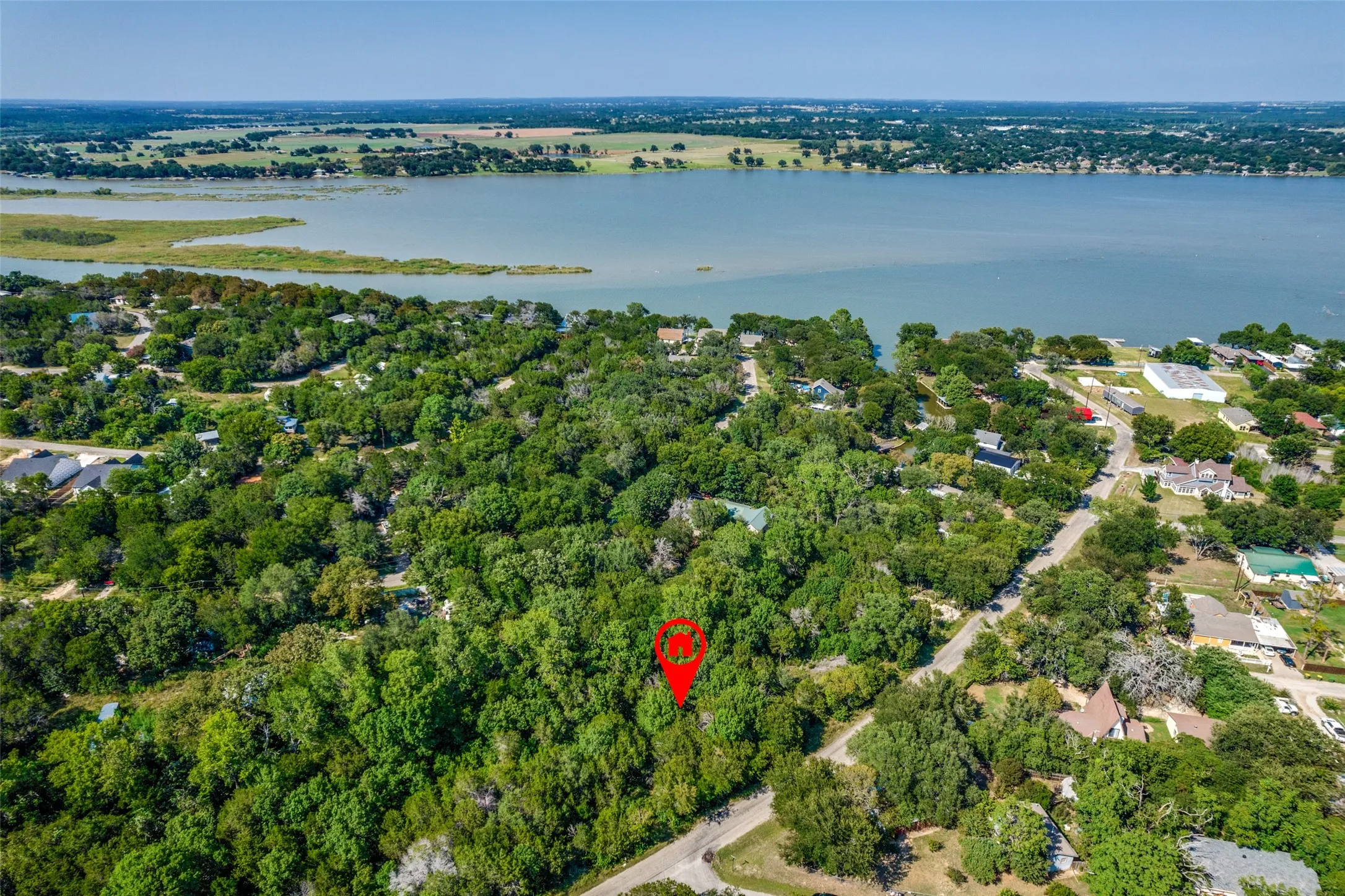 Aerial view showcasing the property's location amidst lush greenery, with a prominent body of water visible in the background