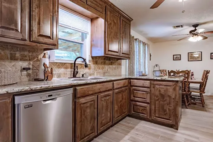 Kitchen with ceiling fan, stainless steel dishwasher, a peninsula, wood tiled floors, and decorative backsplash