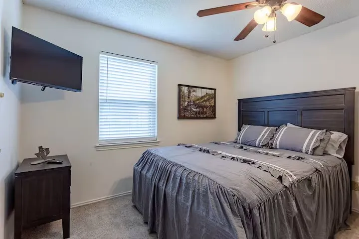 Bedroom with light carpet, ceiling fan, and a textured ceiling
