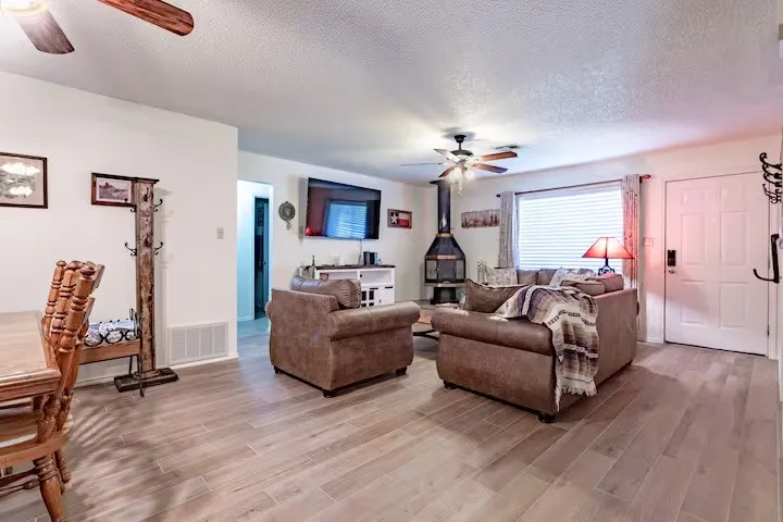 Living area with ceiling fan, a textured ceiling, and wood finished floors