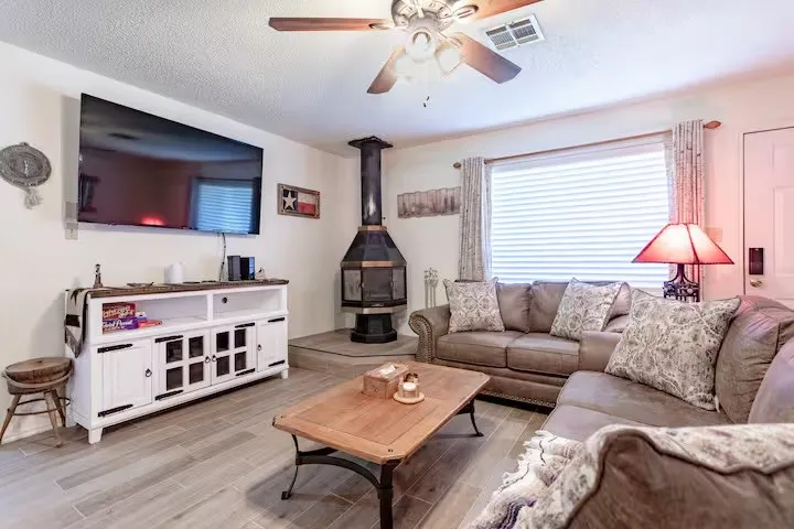 Living area with a ceiling fan, light wood-style floors, a wood stove, and a textured ceiling