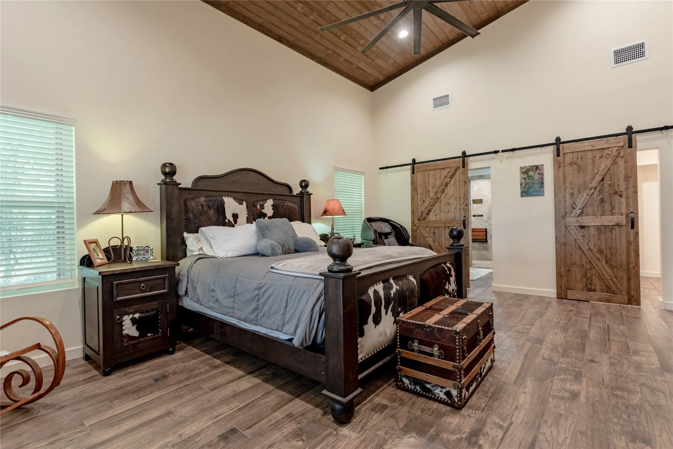 This room features a vaulted wood plank ceiling, wood-look flooring, and windows with blinds