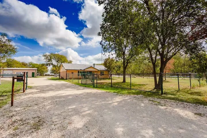 View of dirt / gravel driveway featuring a gate and a gated entry