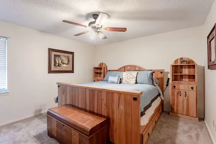 Carpeted bedroom with a ceiling fan and a textured ceiling