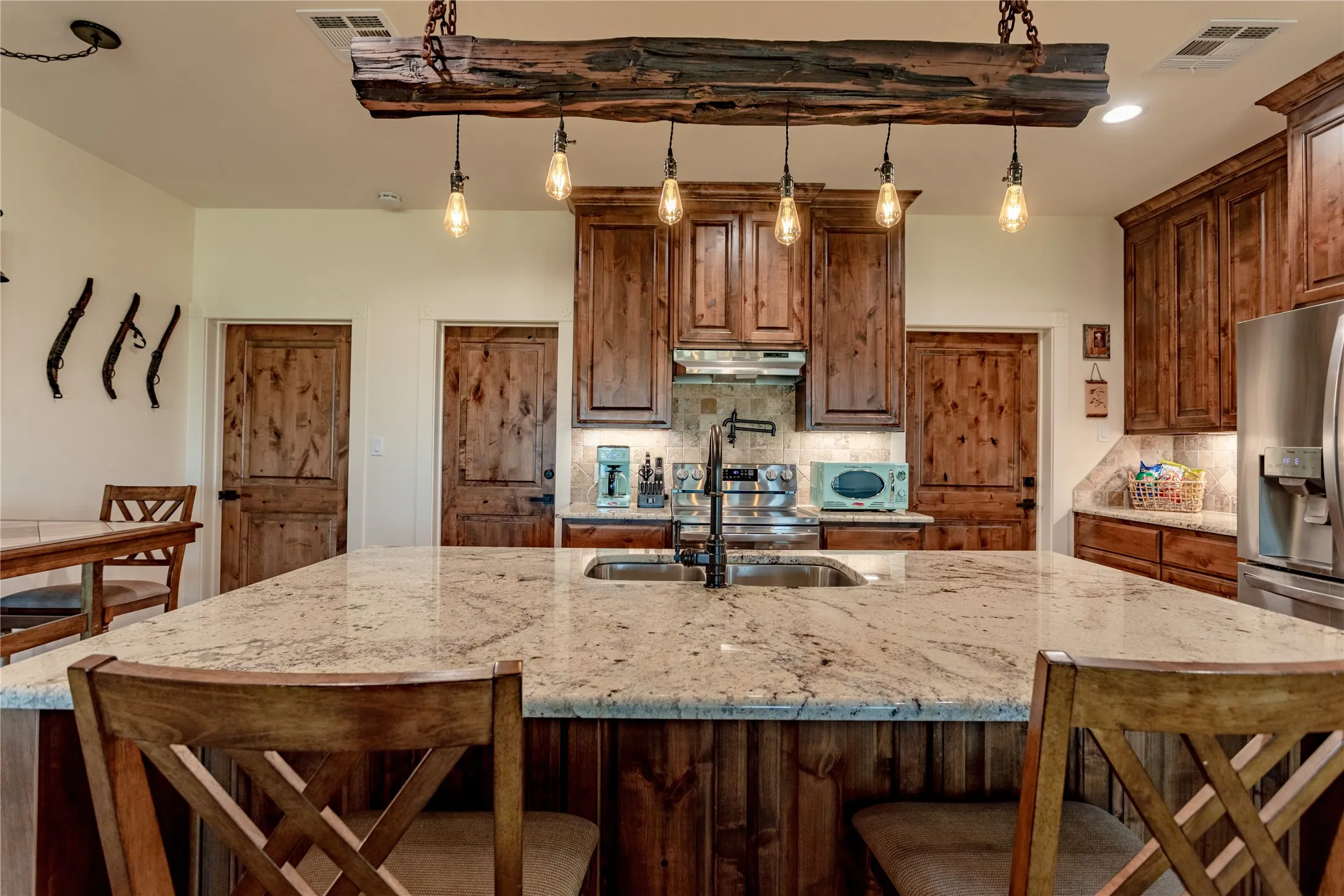 The kitchen features a large island with a granite countertop, a double sink with a gooseneck faucet, and wooden cabinetry
