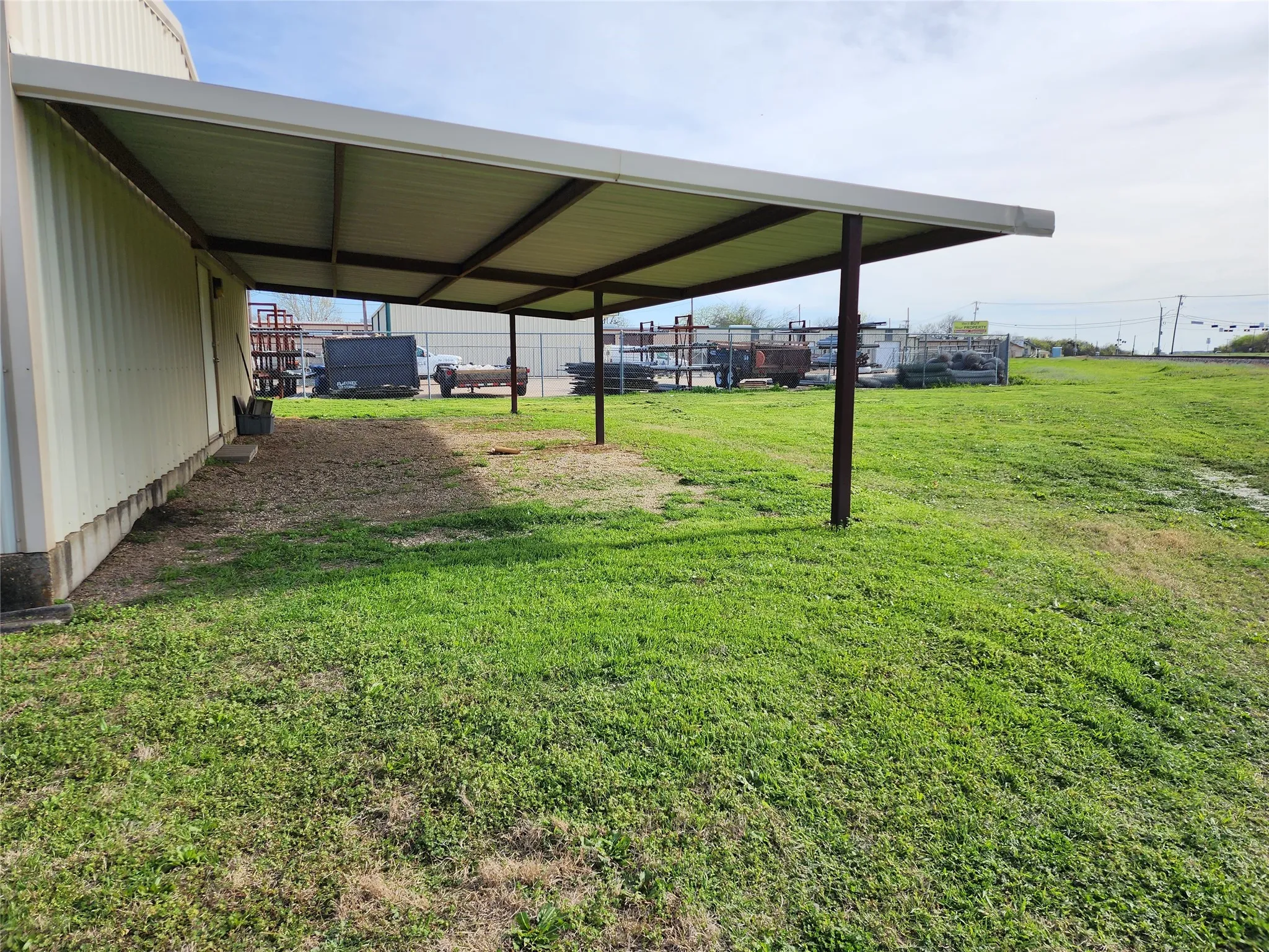 The property features a metal-sided structure with an attached covered awning, providing shaded outdoor space