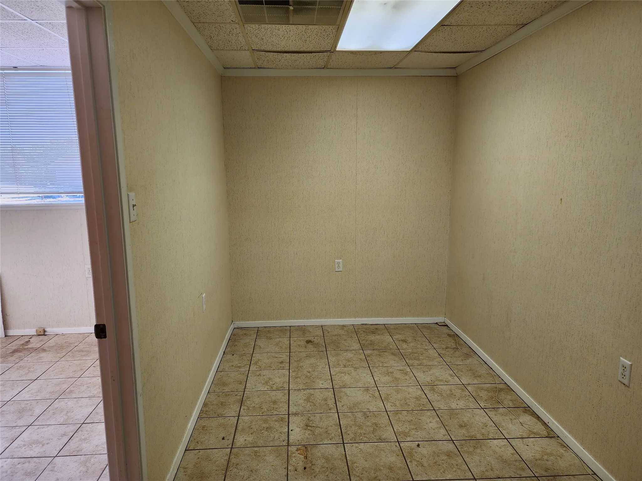 This room features tile flooring and a drop ceiling with integrated lighting