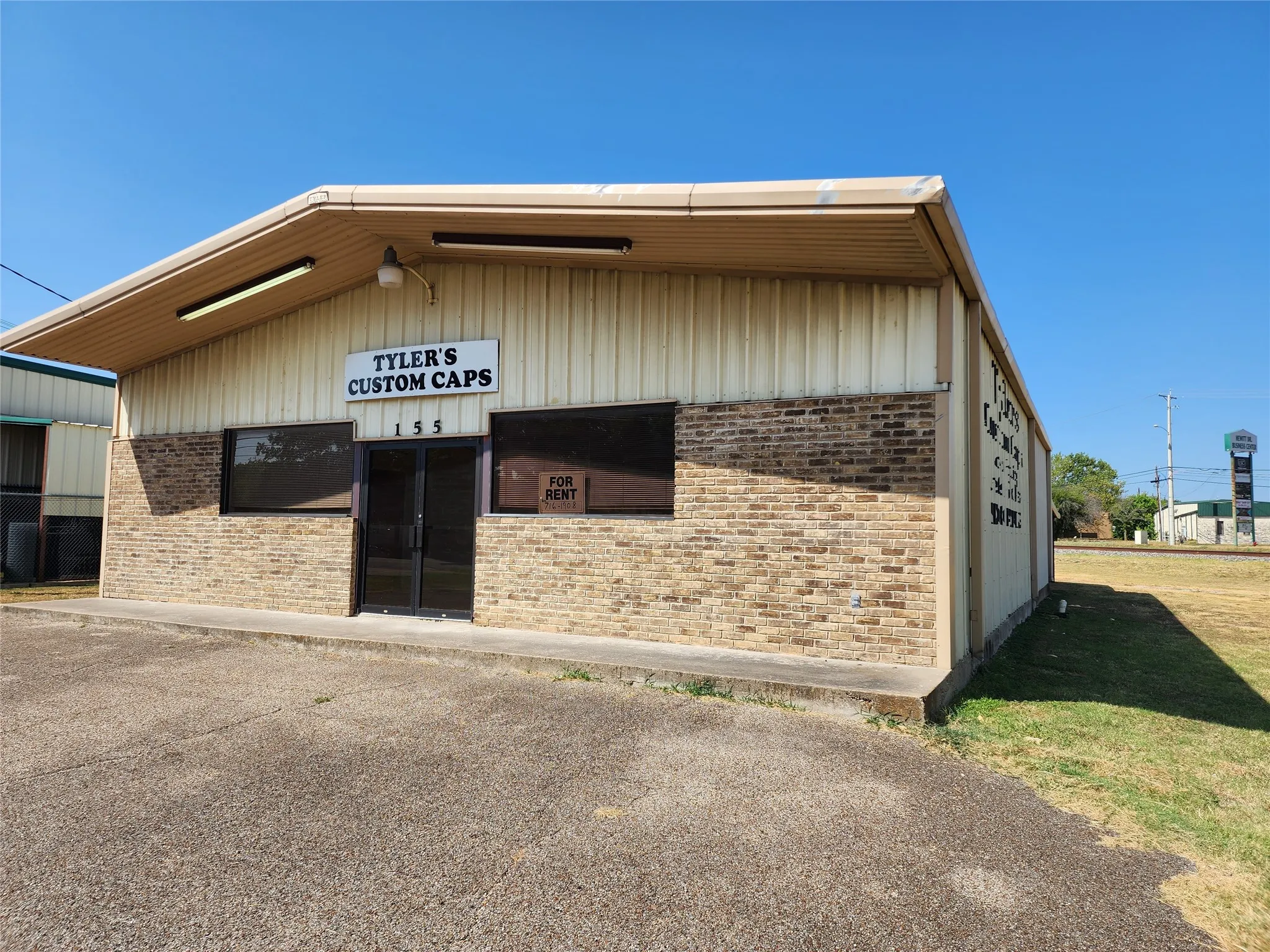 Commercial property with brick and metal siding facade, featuring prominent storefront windows and a glass entry door