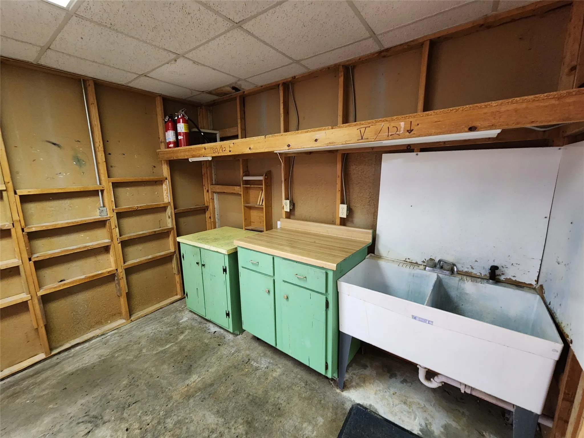 The property includes a utility area featuring a double basin sink, light green cabinetry with wooden countertops, and exposed wooden wall framing