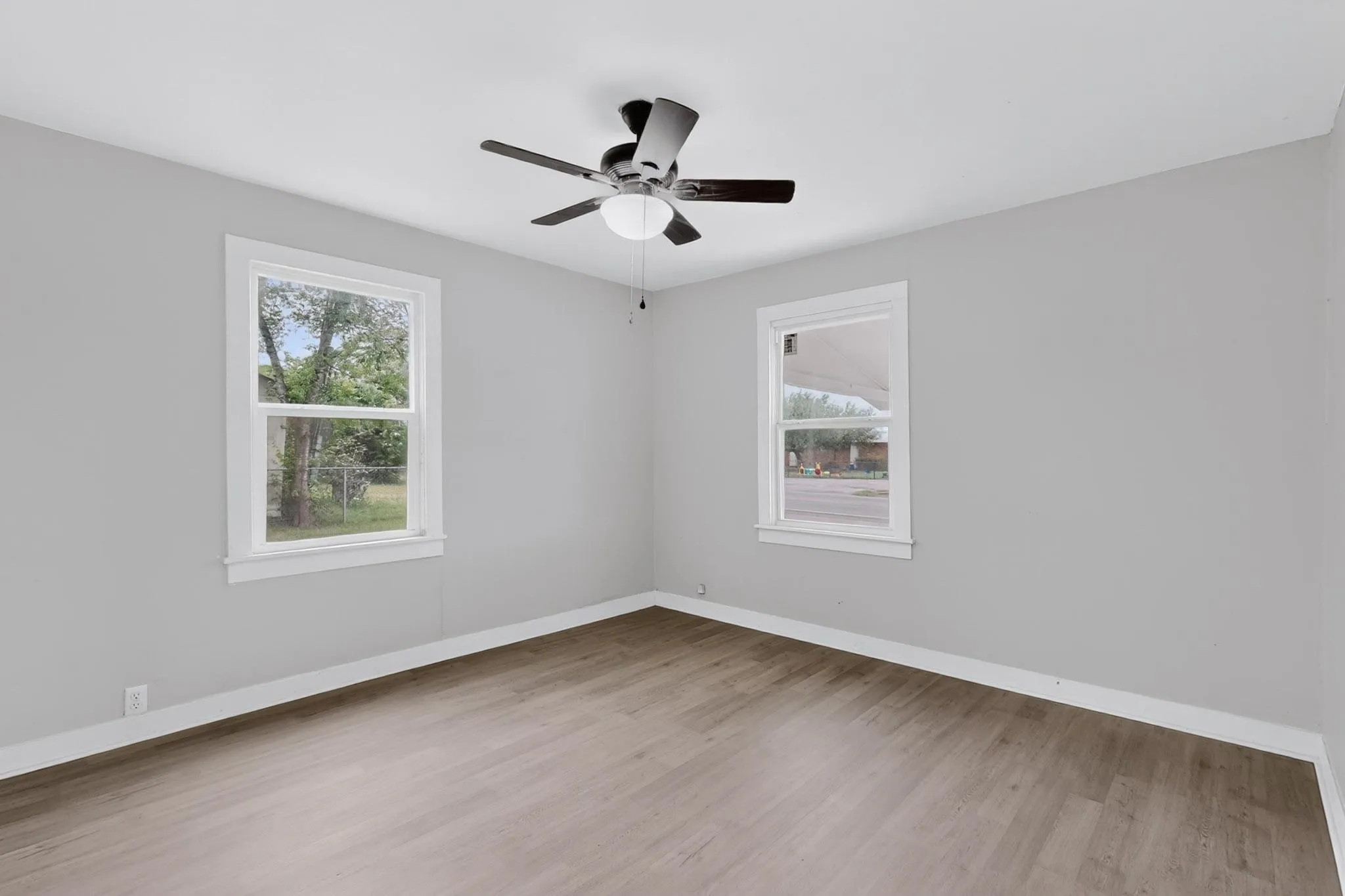 This room features light gray walls, two windows, and wood-look flooring