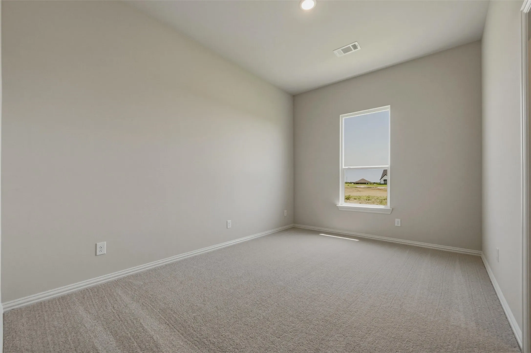 Carpeted room featuring a single window, neutral wall paint, and a recessed ceiling light