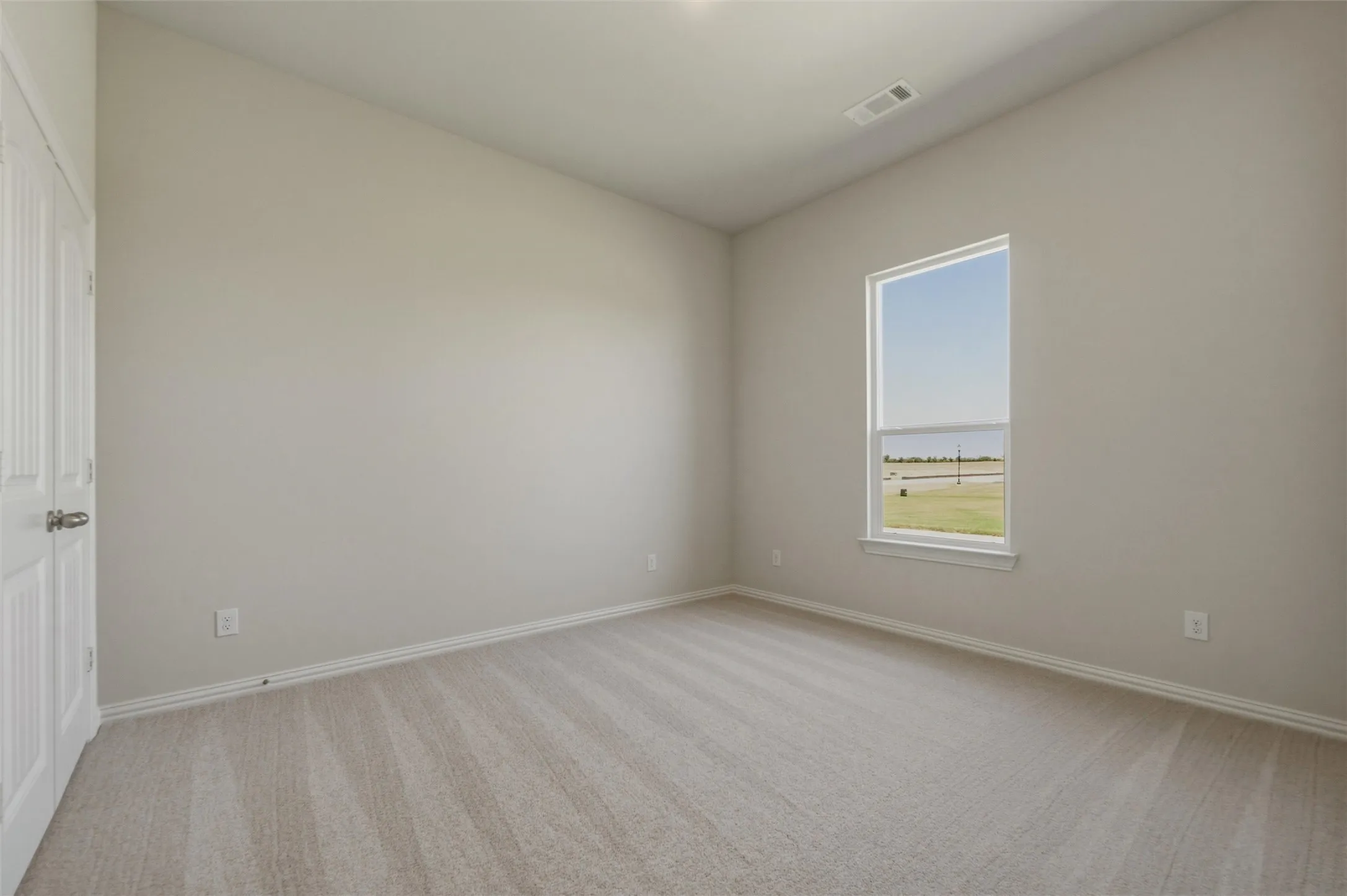 Neutral wall palette, window with exterior scenery, paneled door, and carpet flooring