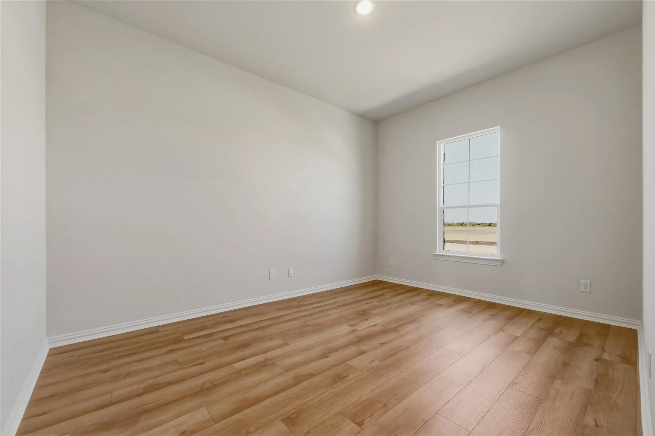 Recessed ceiling lighting, wood-finish flooring, white trim, and a window with white casing