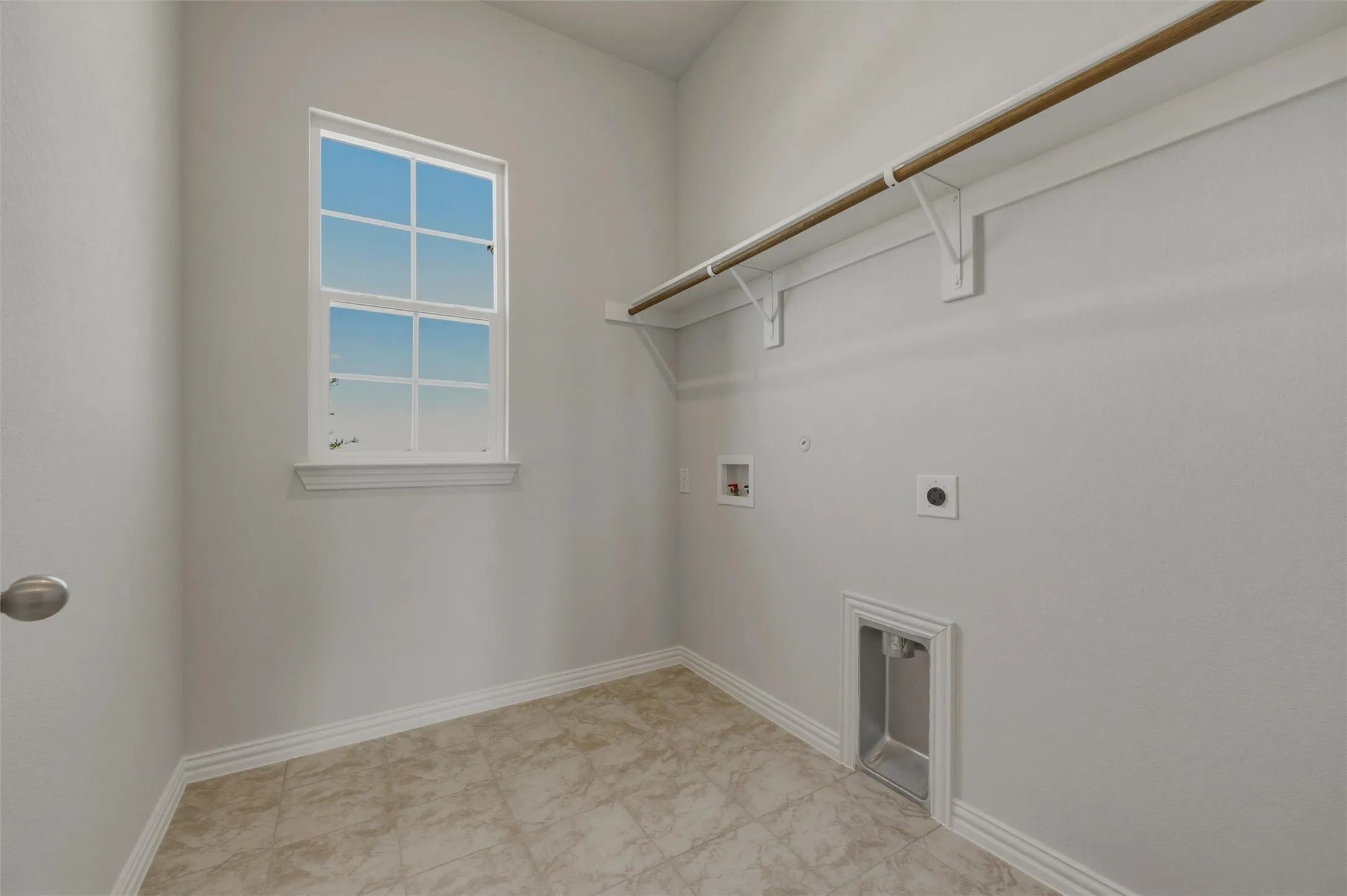 Utility room featuring a window, tile flooring, and integrated laundry hookups