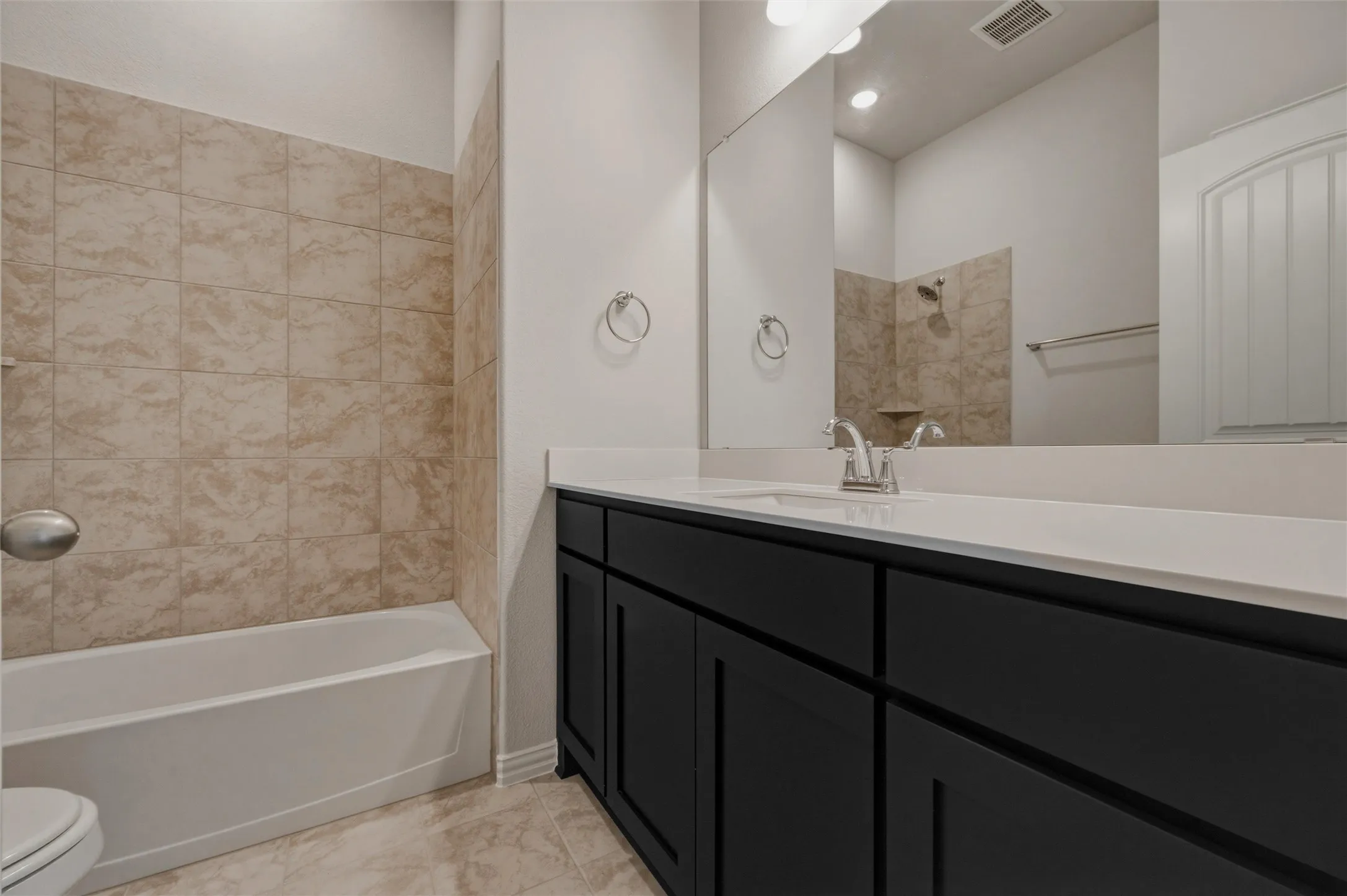 Bathroom featuring a white vanity countertop, dark cabinetry, and tile flooring