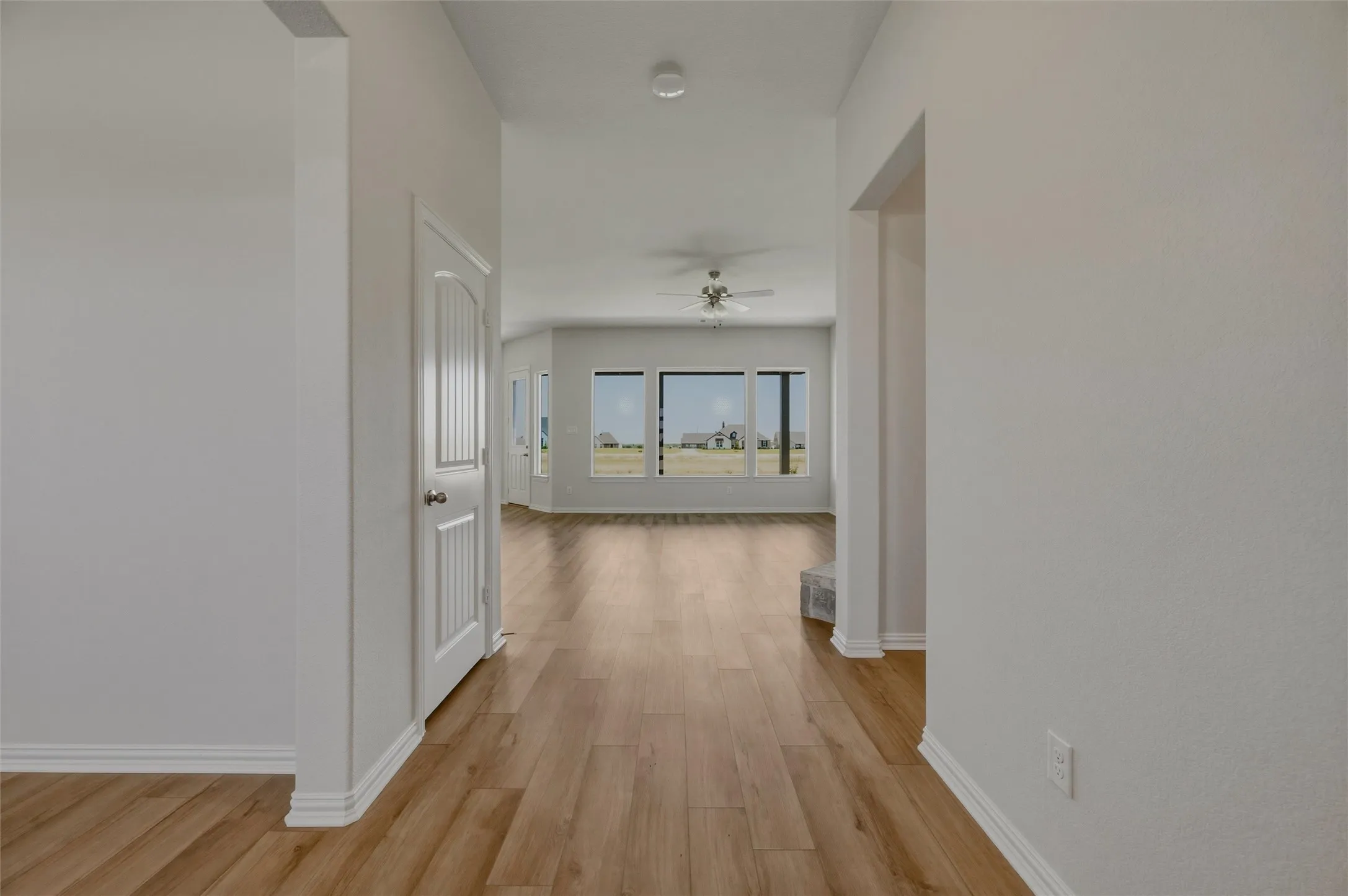 Wood-finish flooring throughout, white interior doors, and multiple large windows with exterior scenery