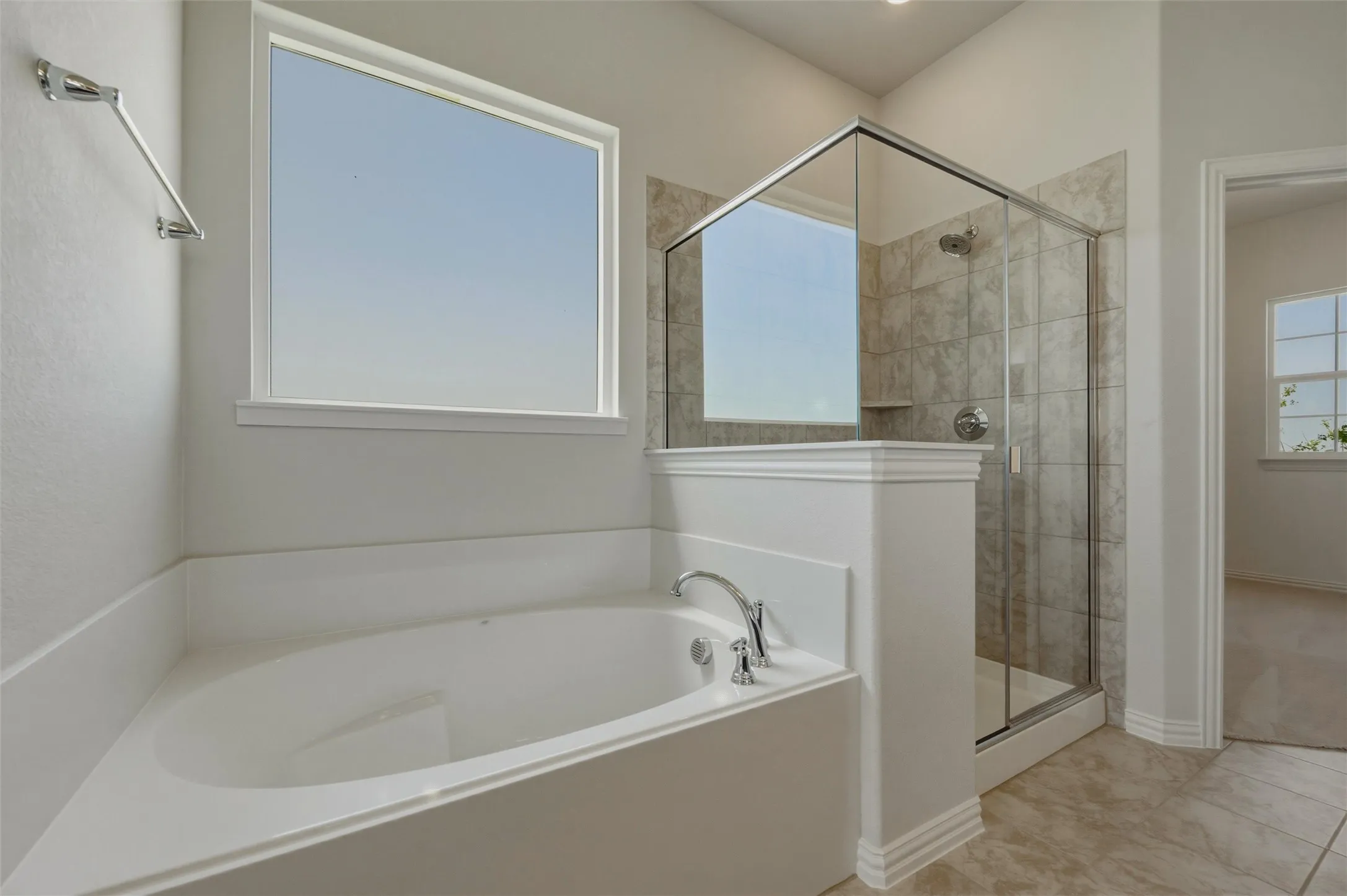 Soaking tub with chrome fixtures and a window with white trim