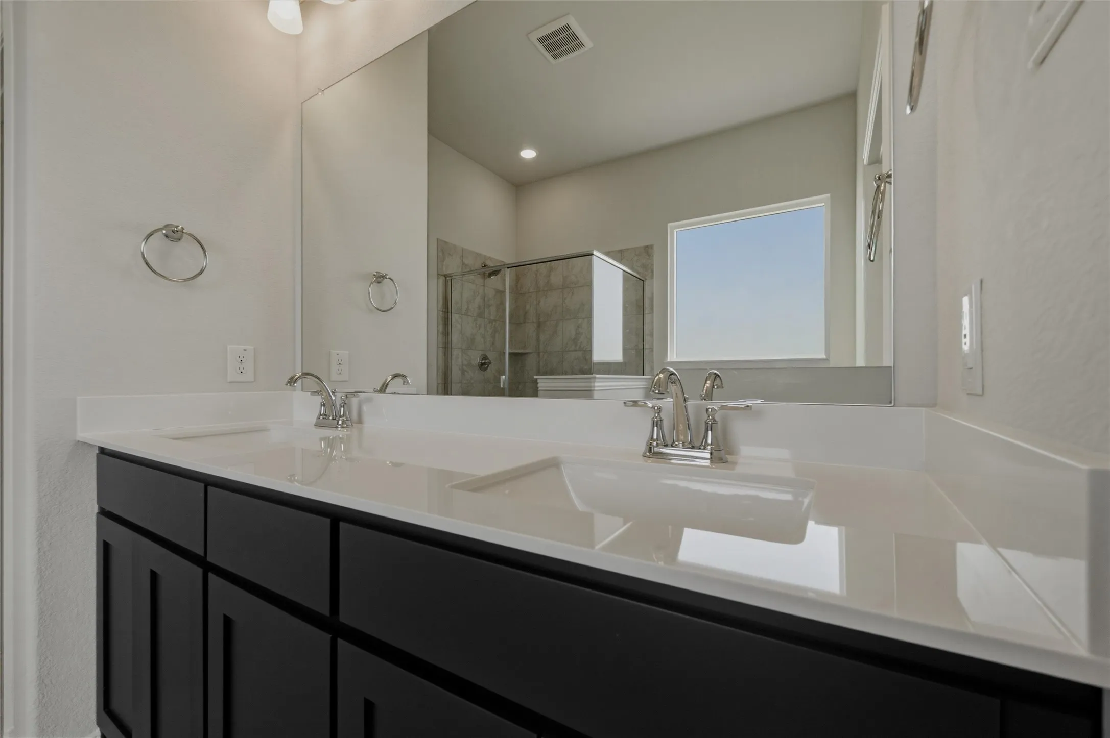 Dual vanity with integrated sinks, chrome fixtures, and dark cabinetry