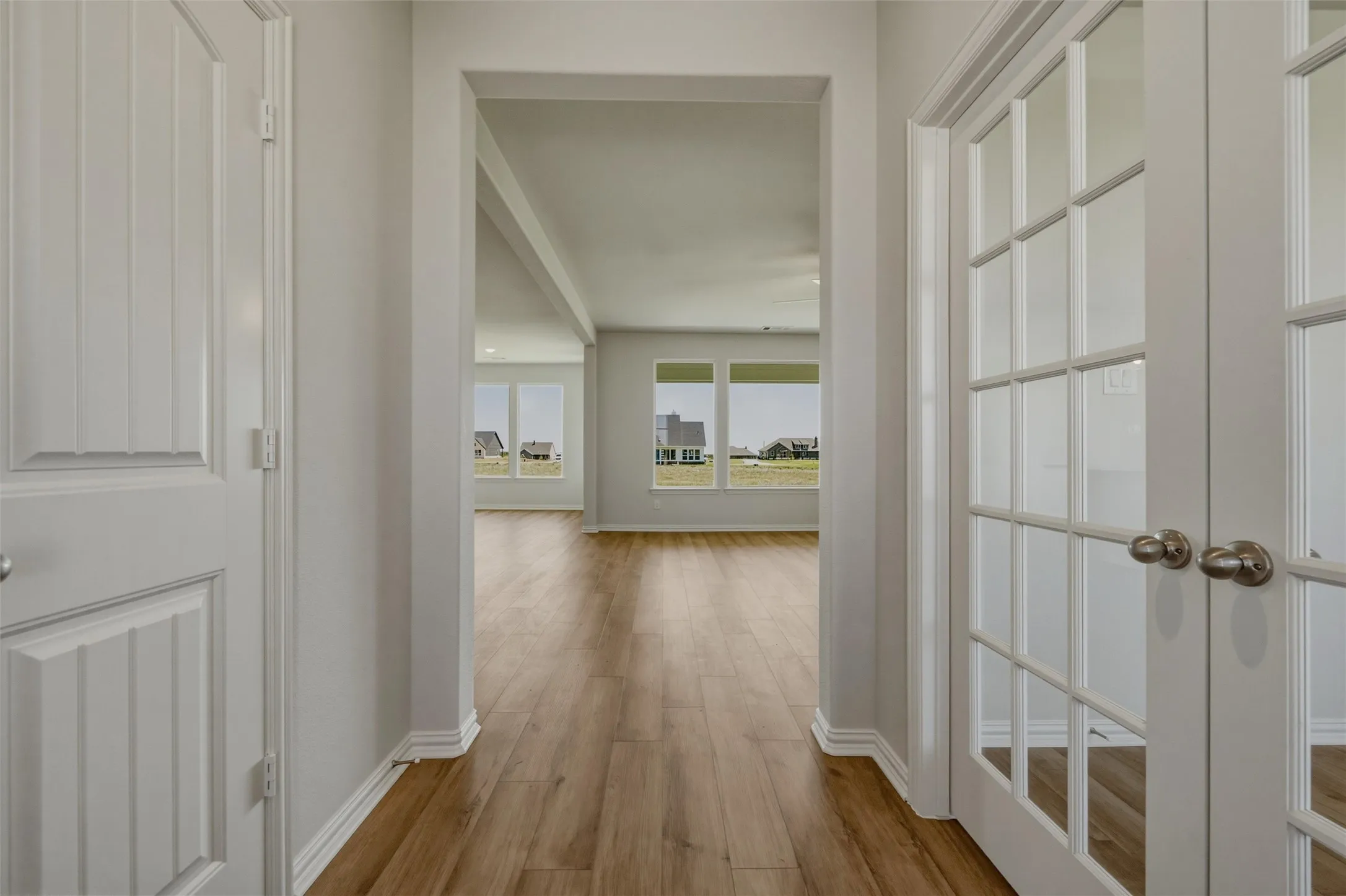 Wood-finish flooring throughout, white interior walls, and multiple large windows for abundant natural light