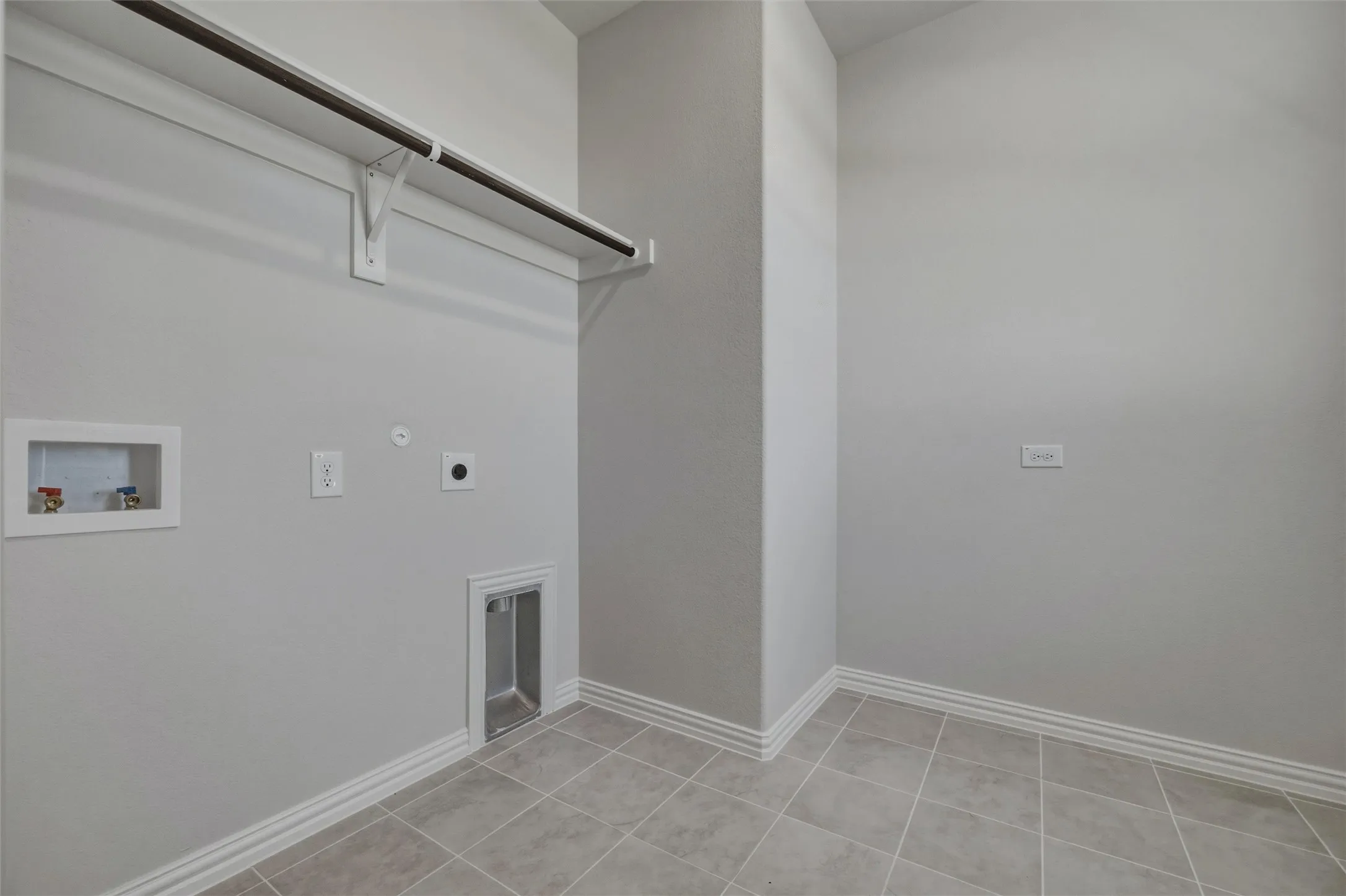 Laundry area featuring tiled flooring and a built-in hanging rod