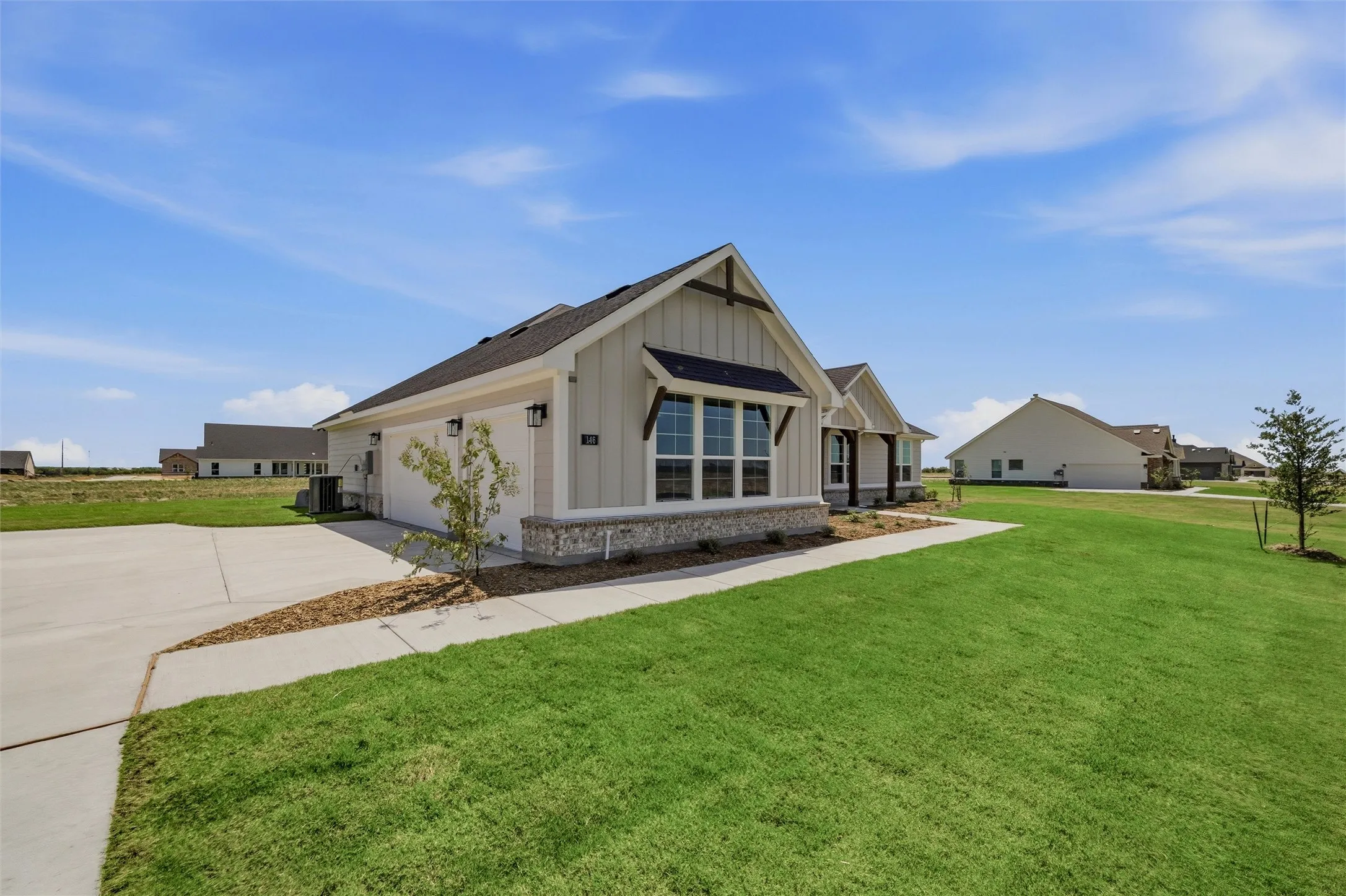 Modern farmhouse with gabled roofline and mixed-material exterior featuring stone and board-and-batten siding