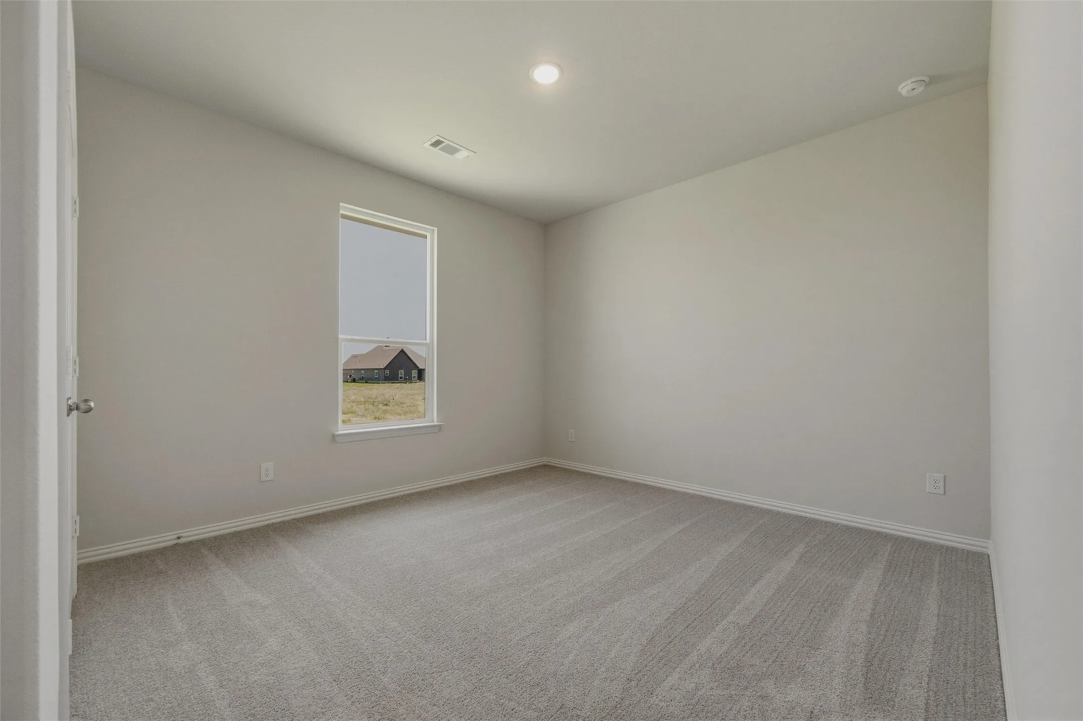 Carpeted flooring, single window with roller shade, recessed lighting, neutral wall tones, and white trim