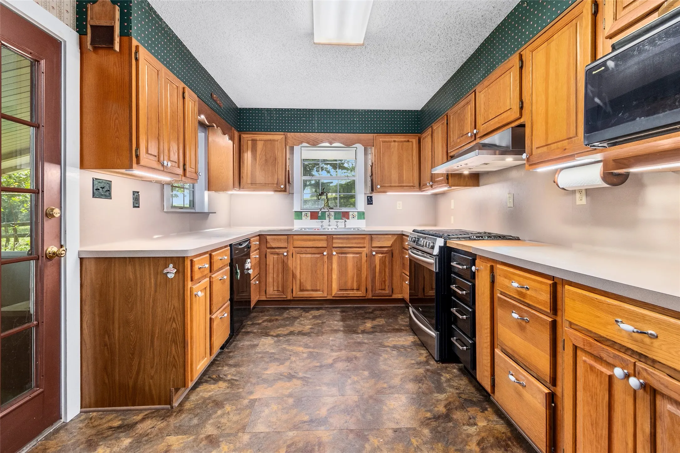 Kitchen featuring appliances with stainless steel finishes, sink, dark tile flooring, and a textured ceiling