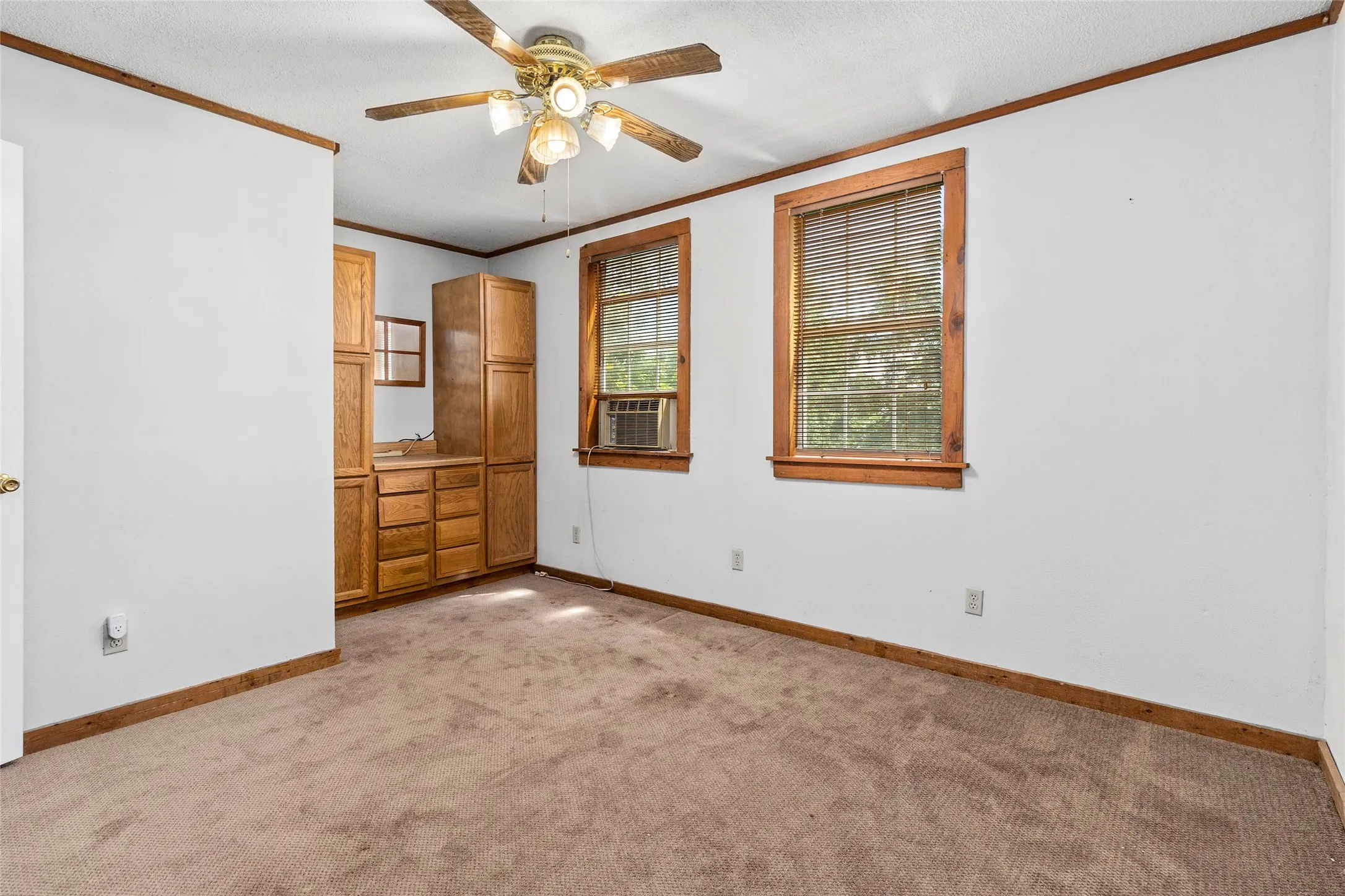 Unfurnished bedroom with ornamental molding, ceiling fan, and light colored carpet