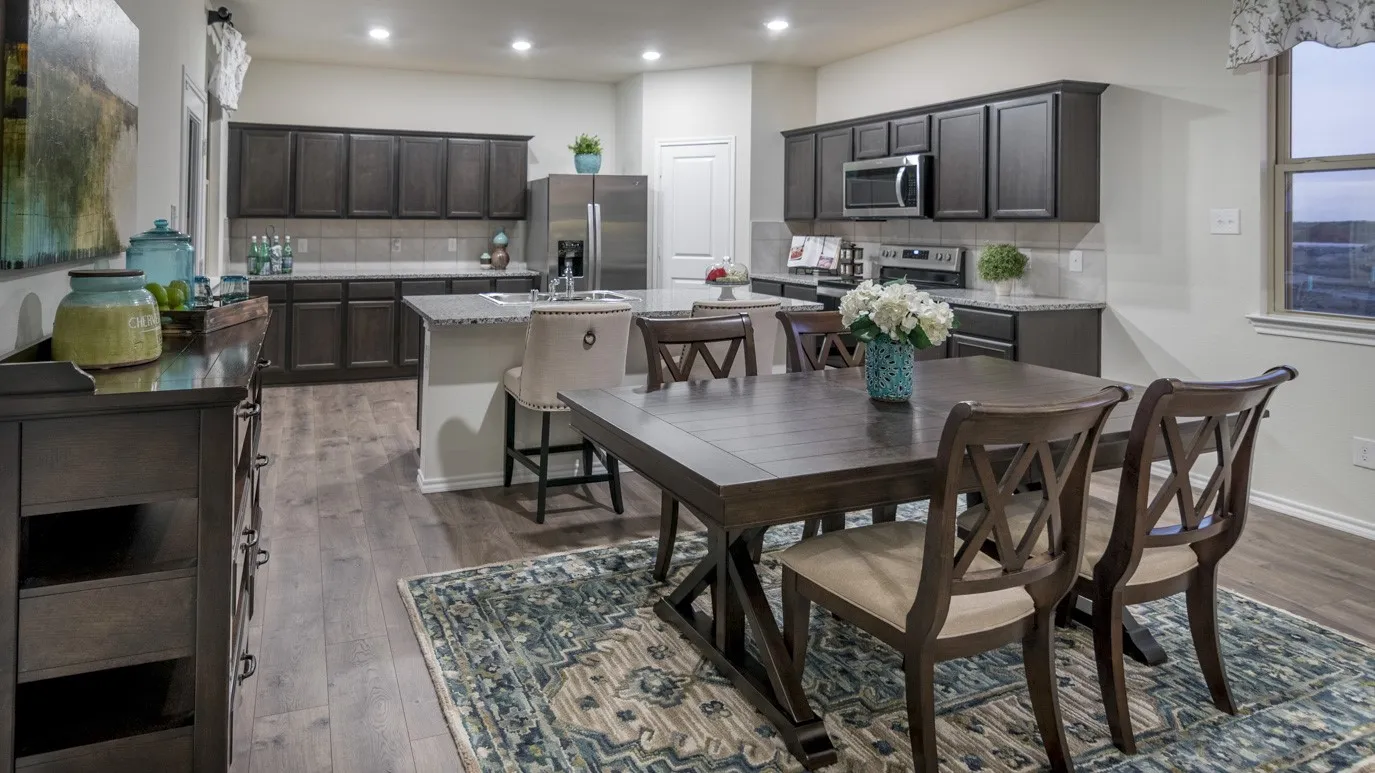 The open-concept kitchen and dining area features dark wood cabinetry, a central island with bar seating, and stainless steel appliances