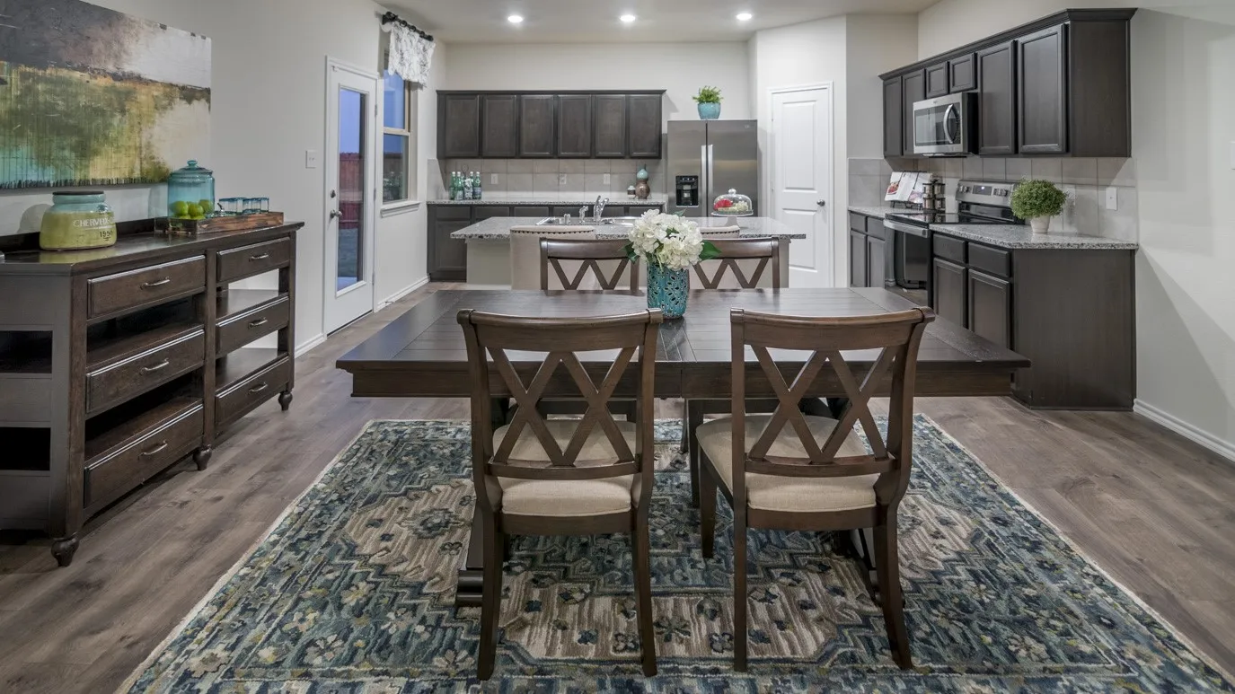Open-concept living space featuring wood-look flooring, a kitchen with dark cabinetry and stainless steel appliances, and a dining area