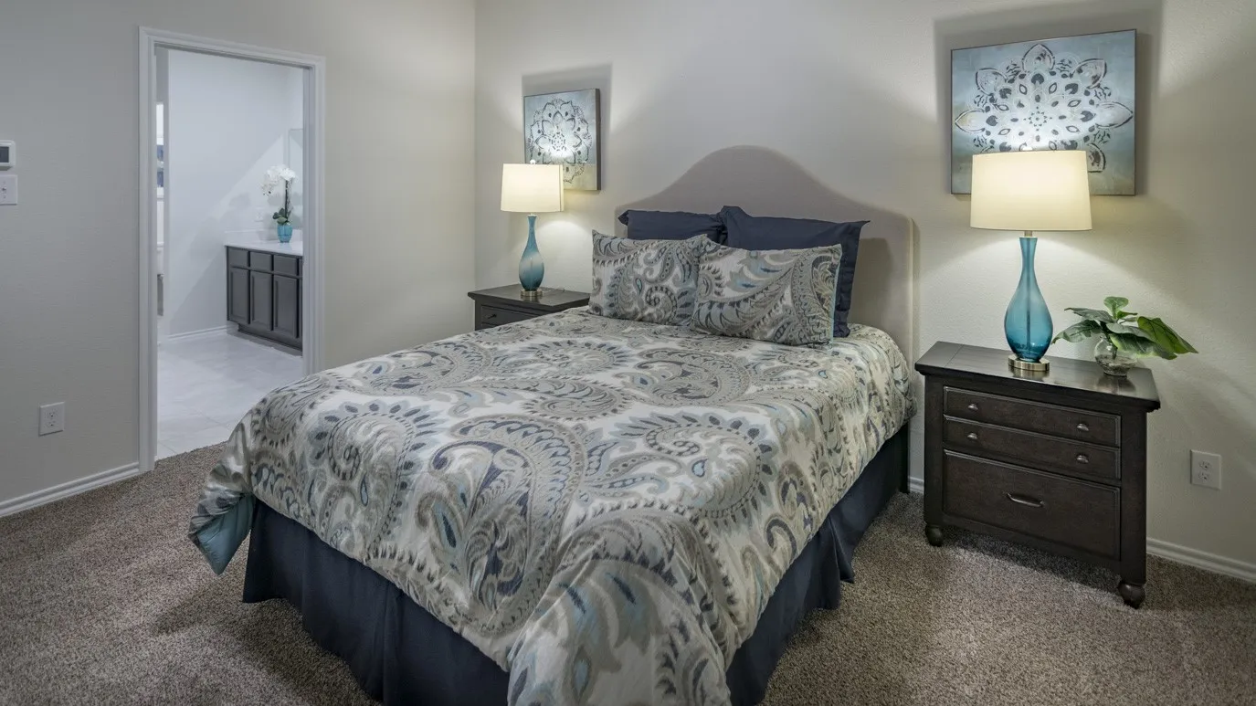 This room features carpeting, a bed with a headboard, and two nightstands with lamps