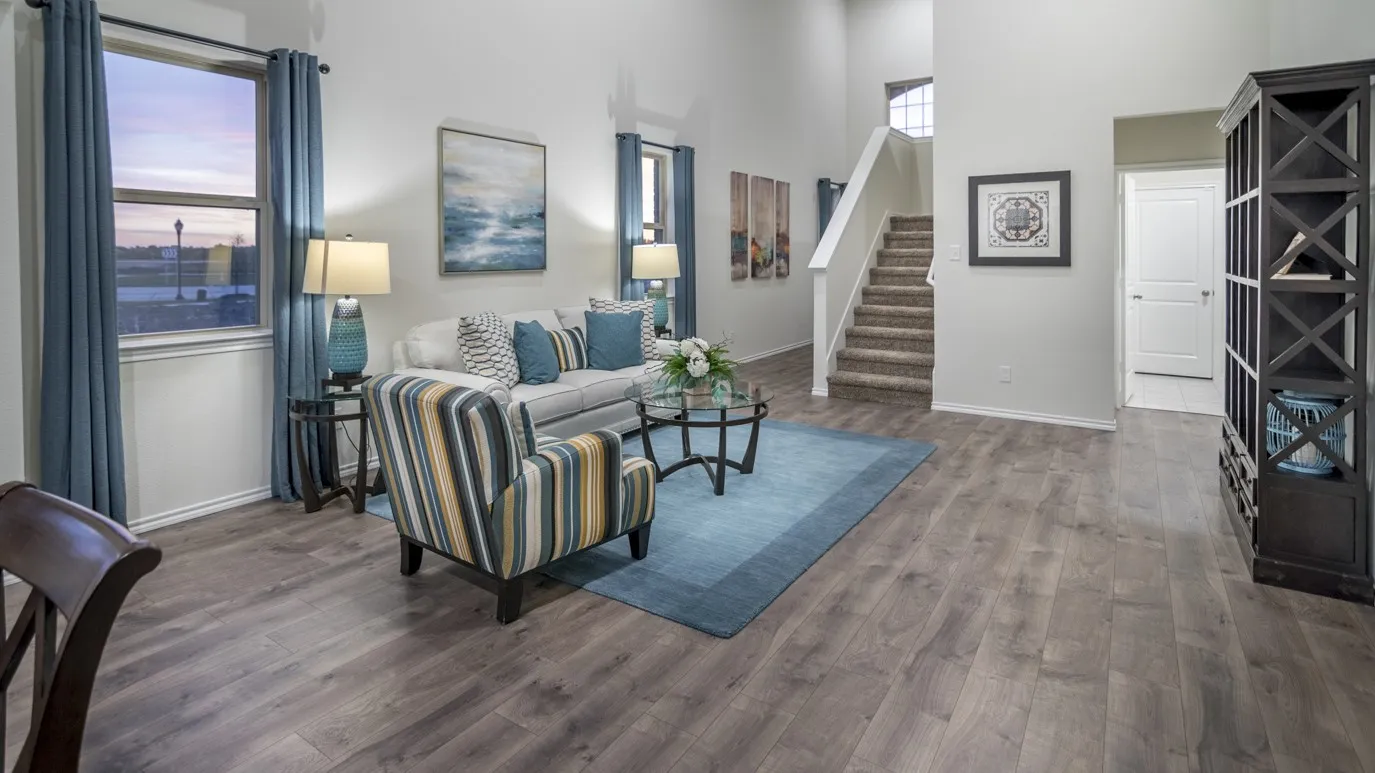 The living area features hardwood floors and high ceilings, with a carpeted staircase visible