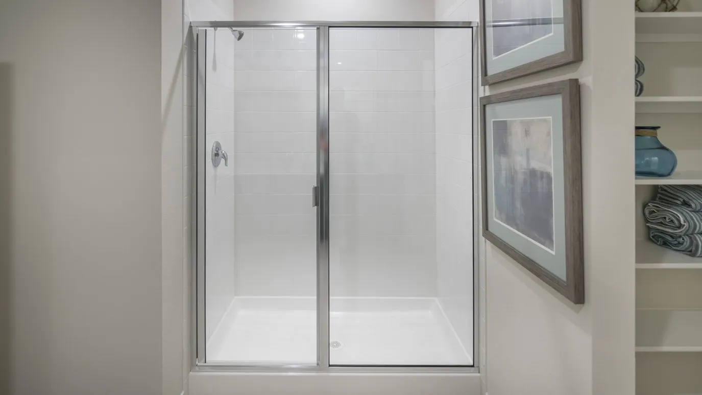 The bathroom features a walk-in shower with a glass enclosure and chrome hardware, and white tiled walls
